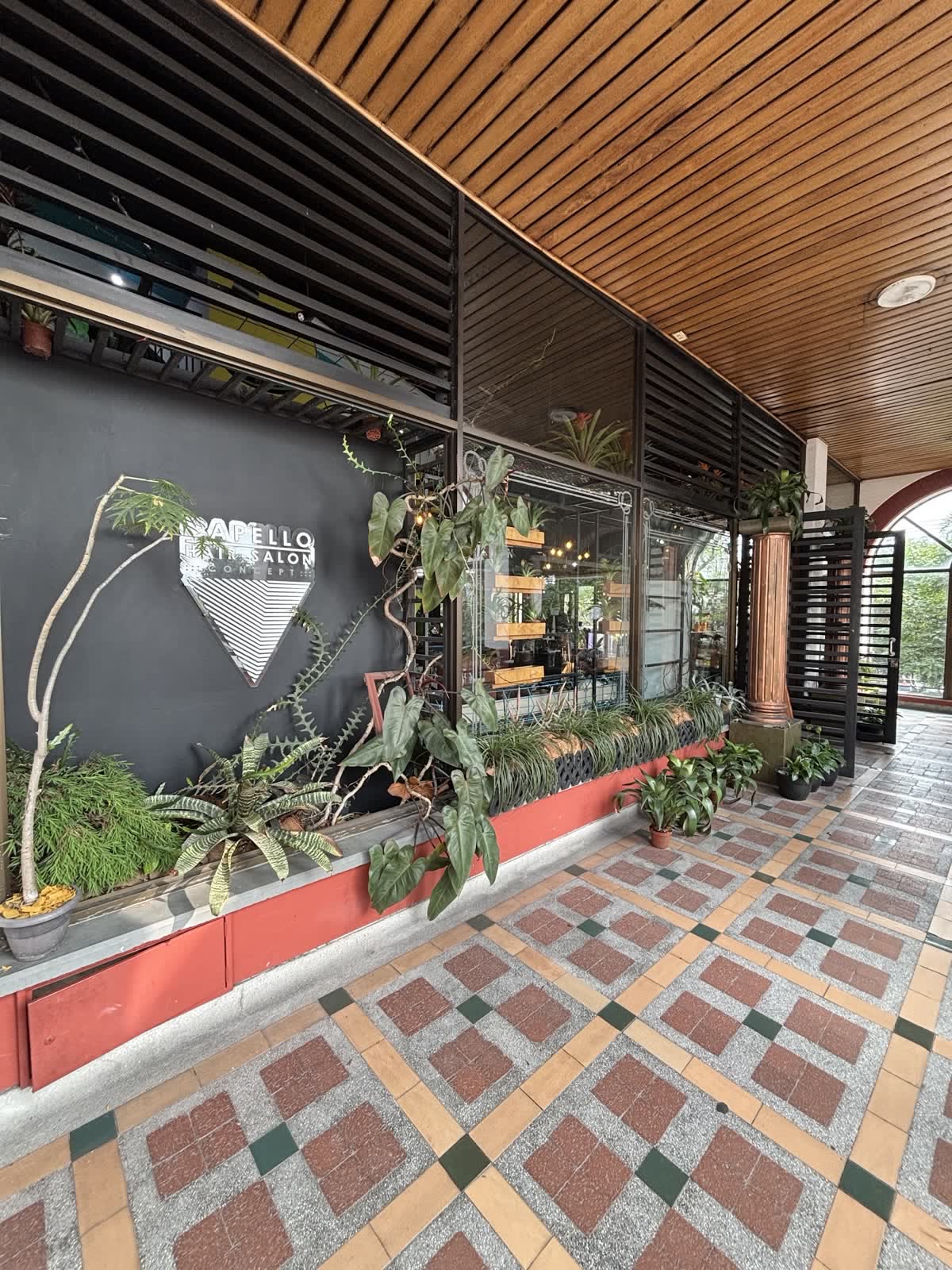 Pasillo con el triángulo del logo, jardín y piso de baldosas